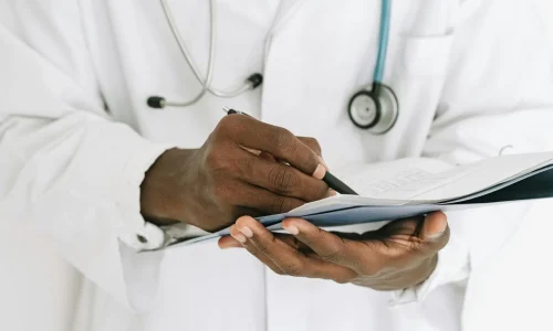 pexels-photo-4989141-4989141 Professional doctor writing on a clipboard with a stethoscope in a medical office.